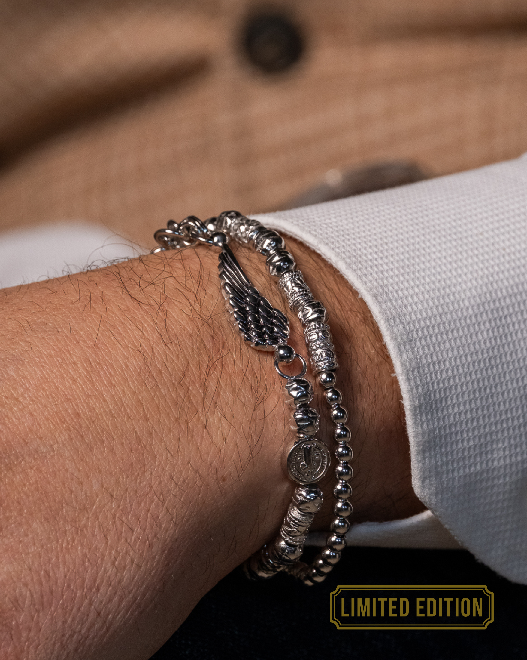 Doppelt drehbares Herrenarmband in Silber mit kleinen und großen Kugeln und individuellem Flügelanhänger